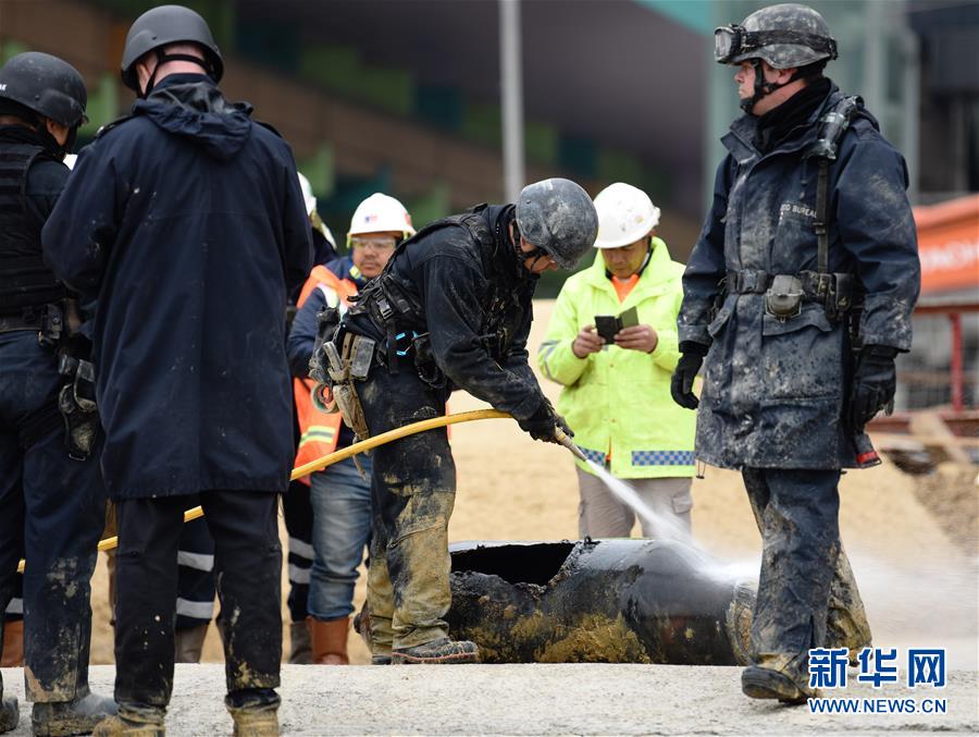 2月1日，在香港湾仔一处工地，香港警方拆弹队员在对弹体喷水。新华社发（王申 摄）