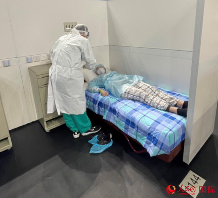 在方舱医院住院区,医护人员为入院的阳性感染者讲解相关设施使用方法。人民网记者 富子梅摄