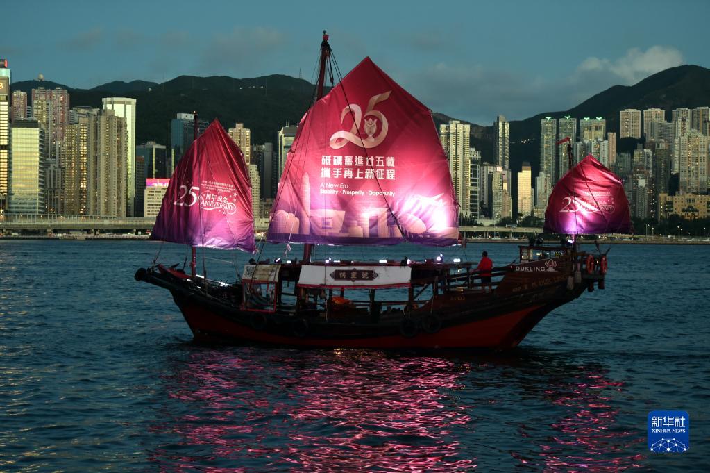 　　一艘帆船挂上庆祝香港回归祖国25周年横幅在维港航行（6月23日摄）。