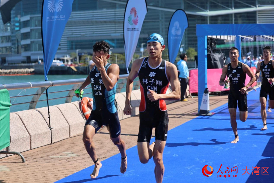 铁人三项男子个人赛选手游泳上岸后奔向自行车项目转换区。人民网记者 冯学知摄