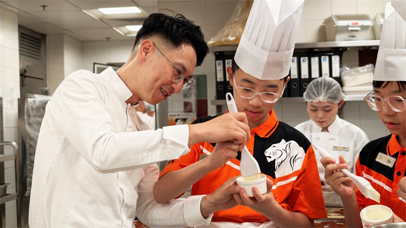 图为吴梓佑同学(左二)在父亲吴永谋(左一)指导下制作甜品。主办方供图