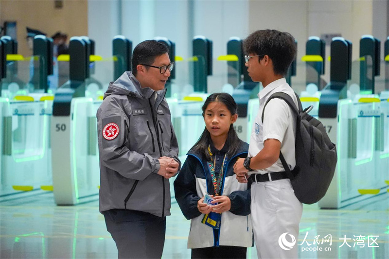 图6：香港特区政府保安局局长邓炳强向旅客询问过关情况。人民网 吴宇扬扬摄