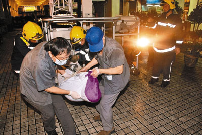 消防员及仵工将堕楼女子遗体抬走。