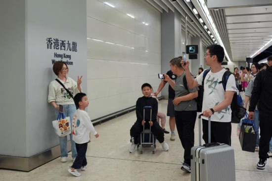   5月1日，乘客乘坐北京西-香港西九龙G79次列车抵达香港西九龙站后与站牌合影。新华社记者 郑焕松 摄