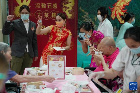 5月24日，在香港松悦园耆和护养院，香港乐龄社企“软餐侠”的职员们扮演成“茶楼”经理、厨师和接待员，为老人家提供沉浸式茶楼就餐体验。新华社发（王申 摄）
