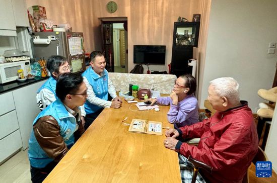 11月18日,穆家骏(前左)与关爱队成员在湾仔利昌大厦走访社区长者。新华社记者 陈铎 摄