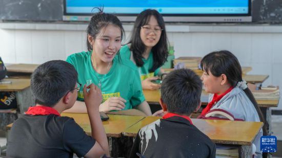 香港理工大学学生在麻栗坡县大坪小学与当地学生交流（5月12日摄）。新华社发