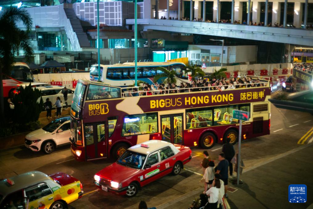 2月20日，在香港中环船埠外，游客乘坐“落日飞车”游览。新华社记者 朱炜 摄